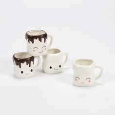 four coffee mugs with faces painted on them