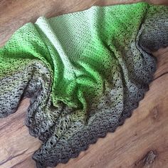 a green and grey blanket laying on top of a wooden floor