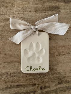 a ceramic ornament with a bow on it that says charlie and has paw prints