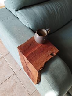 a cup is sitting on top of a piece of wood that has been placed on the couch