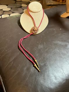 a hat and necklace sitting on top of a black leather table next to a wooden mannequin