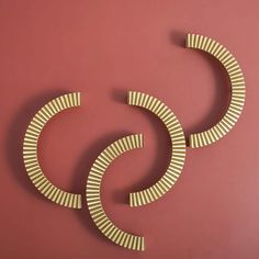 two circular metal sculptures on a pink wall