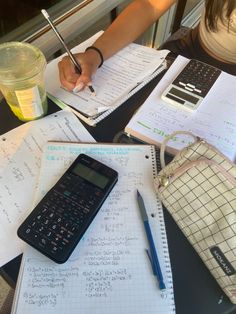 a person sitting at a table with notebooks and calculator