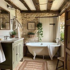 an old fashioned bathtub in a rustic bathroom with stone walls and exposed wood beams