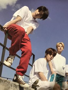 three young men sitting and standing on top of steps with their feet in the air