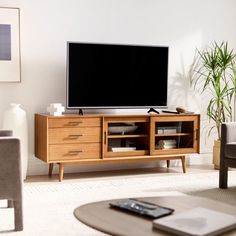 a flat screen tv sitting on top of a wooden entertainment center in a living room