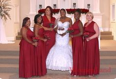 a group of women standing next to each other in front of a white wall with red flowers