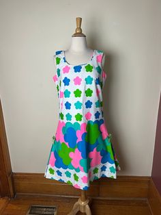 Vintage 60s Princess Kaiulani mod psychedelic Hawaiian mini dress. Incredible pops of color on this Princess Kaiulani mini dress! Cool floral shape in bright pink, teal, blue, and two shades of green. Zip closure in back, sleeveless, side kick pleats with green bows at top, hits at knees. Somewhat a-line shape with a flare to the skirt portion, but slimmer fit across the rear nonetheless. No material tag listed, but I can confidently say this one is 100% thick, sturdy cotton. No size listed, but Retro Colorful Dresses With Vibrant Print, Colorful Retro Dresses With Vibrant Print, Retro Dresses With Vibrant Print, Mod Style Multicolor Mini Dress For Spring, Retro Multicolor Knee-length Mini Dress, Retro Green Dress With Vibrant Print, Vibrant Green Mini Dress, Retro Multicolor Mini Dress With Floral Print, Groovy Fitted Multicolor Dress