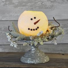 a snowman made out of pineapple sitting in a silver vase on a wooden table