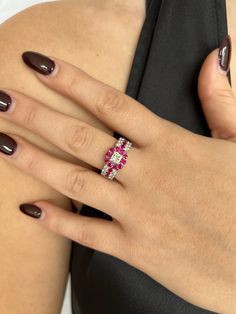 a woman's hand wearing a ring with pink stones on it and brown nails