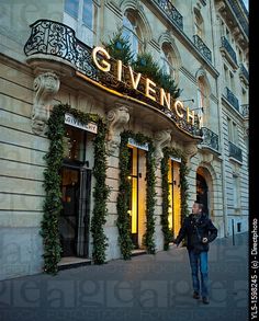 a man walking down the street in front of a building with ivy growing on it