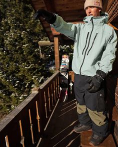 a man standing on top of a wooden platform wearing skis and holding his arms out