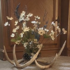 a vase filled with flowers and antlers on the ground