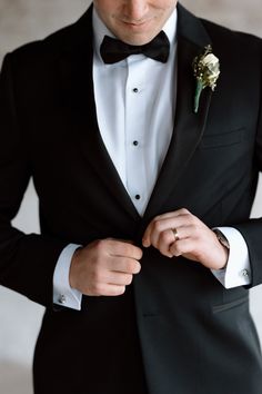 a man in a tuxedo adjusts his bow tie