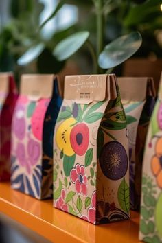 colorful bags lined up on a table next to a potted plant