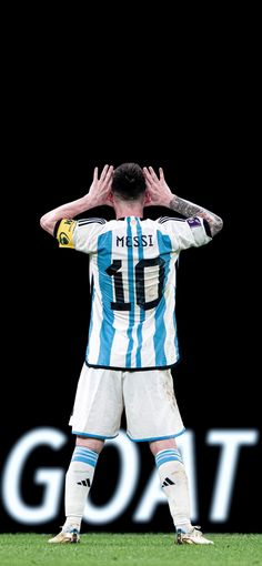 a soccer player is covering his face with his hands while standing in front of the word goal