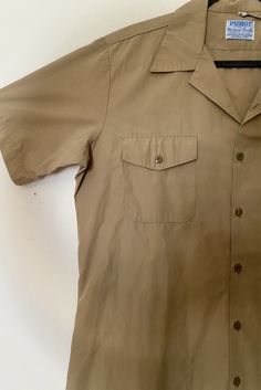 Color: Khaki Brand: Patriot styled by Weintraub Bros. Co. Made in USA 65% Polyester, 35% Cotton Casual Beige Tops With Roll-up Sleeves, Classic Short Sleeve Button-up Shirt With Snap Buttons, Relaxed Fit Top With Button Cuffs And Camp Collar, Casual Solid Shirt With Buttoned Pockets, Casual Beige Tops With Snap Buttons, Button-up Summer Tops With Buttoned Pockets, Solid Color Button-up Top With Buttoned Pockets, Summer Button-up Tops With Buttoned Pockets, Beige Shirt With Buttoned Pockets