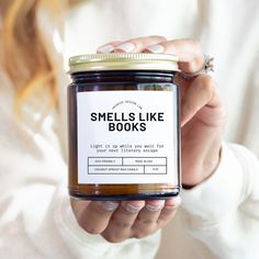 a woman holding a jar of smells like books