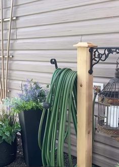 a garden hose is attached to the side of a house in front of a birdcage