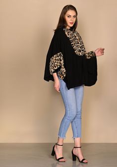 This black collared cape is knitted from a very soft fine wool and is one of a kind. Its uniqueness is in its versatility with the many ways that it can be styled. But that's not all it has contrasting leopard fur applications on the bust and sleeves that makes it a head-turner. Classy stylish and comfortably warm. Black Stretch Turtleneck Outerwear, Chic Black Wool Cape, Oversized Cashmere Poncho, Chic Oversized Cashmere Cape, Oversized Chic Wool Poncho, Chic Black Turtleneck Outerwear, Oversized Cashmere Cape With Long Sleeves, Oversized Wool Poncho With Long Sleeves, Black Batwing Sleeve Sweater For Layering