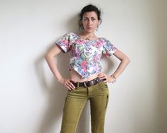 Super-cute 80's cropped blouse with short sleeves. Made in USA by S. L. Petites. Blooming roses painting print in soft pink and blue on white. Buttons down the front. Fabric: 100% cotton. Short raglan sleeves. Cropped length and pointed waist. Tagged size US10. Estimated size XS to S, the model is size XS, please make your judgement from the measurements below: armpit  ~ 90 cm  /  ~ 35 " waist  ~ 78 cm  /  ~ 30 " length  ~ 43 cm  /  ~ 17 " by the back In great vintage condition. 90s Style Short Sleeve Crop Top For Summer, 90s Style Short Sleeve Crop Top, Fitted Short Sleeve Cropped Shirt For Spring, Fitted Cropped Shirt With Short Sleeves For Spring, 90s Style Cropped Summer Crop Top, Cropped 90s Style Summer Crop Top, 90s Style Cropped Crop Top For Summer, Retro Short Sleeve Crop Top For Spring, Retro Fitted Short Sleeve Crop Top