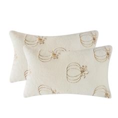 two pillows with decorative designs on them, one in white and the other in gold