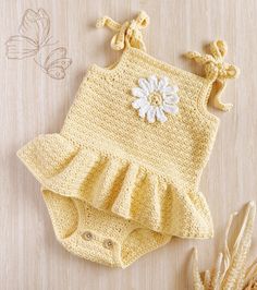 a crocheted yellow outfit with white flower on it and some corn stalks next to it