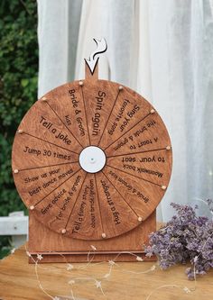 a wooden spinning wheel with the names of different languages on it and some lavender flowers