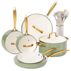 an assortment of green and white pots, pans and utensils with gold handles