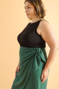 a woman in a black top and green skirt with her hands on her hips, posing for the camera