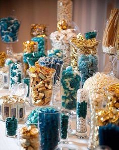 a table topped with lots of candy covered in blue and gold candies next to candles