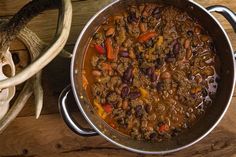 a large pot filled with meat and vegetables on top of a wooden table next to antlers