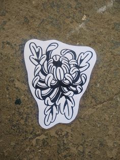 a sticker that is sitting on the ground next to a piece of paper with an image of flowers