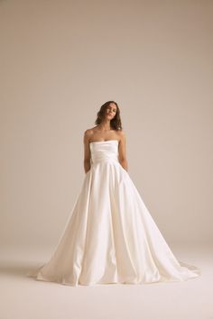 a woman in a white wedding dress posing for the camera with her hands on her hips