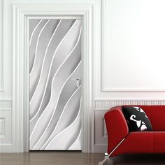 a red chair sitting in front of a white door with abstract designs on it's side