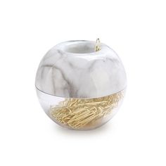 a white marble apple with gold colored noodles in it's bowl on a white background