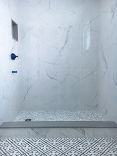 a bathroom with white marble walls and tile flooring, including a walk in shower