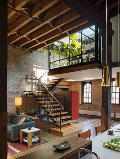 a living room filled with furniture and a spiral staircase in front of a brick wall