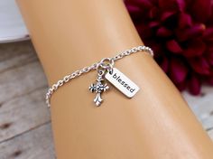 "This elegant and simple Cross Blessed Bracelet features a sterling silver Cross Charm and a sterling silver Blessed Charm on a sterling silver chain finished with a lobster clasp closure. Bracelet is solid sterling silver, fully adjustable and comes with the option to add a personalized printed gift tag. A beautiful design of scroll work enhances this classic cross. BRACELET DETAILS: * Strong sterling silver cable chain finished with a secure lobster clasp closure * Bracelet is adjustable with Engraved Silver Rosary Bracelet As Gift, Inspirational Silver Charm Bracelet For Mother's Day, Inspirational Sterling Silver Nickel-free Bracelets, Spiritual Silver Charm Bracelet For Mother's Day, Mother's Day Silver Spiritual Charm Bracelet, Mother's Day Spiritual Silver Charm Bracelet, Inspirational Hypoallergenic Silver Bracelets, Personalized Silver Rosary Bracelet For Mother's Day, Blessed Bracelet