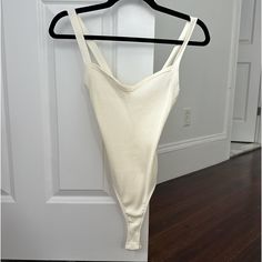 a white top hanging on a hanger in front of a door