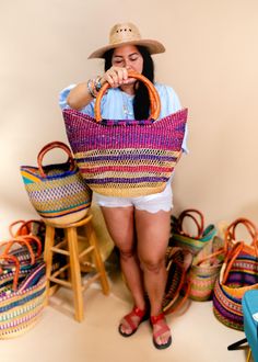 a woman in white shorts and a straw hat is holding a large woven basket over her face