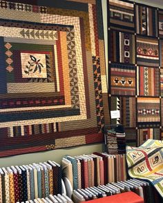 quilts are displayed on the wall in this room with many different colors and patterns