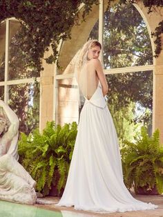 a woman in a wedding dress standing next to a statue