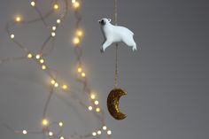 a polar bear ornament hanging from a string next to a tree with lights