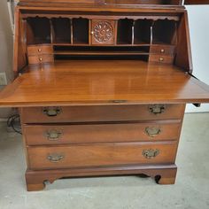 an old wooden desk with drawers and a clock on top