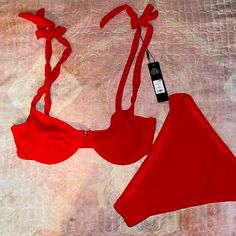 two red bras on a bed with a tag attached to the bra and strap