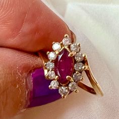 a woman's hand holding a ring with an oval shaped ruby and diamond center