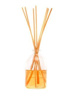 an orange reed diffuser in a clear glass vase filled with yellow liquid and wooden sticks