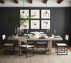 a dining room table with chairs and pictures on the wall above it, along with a potted plant