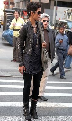 a woman walking across a street next to a cross walk with people in the background